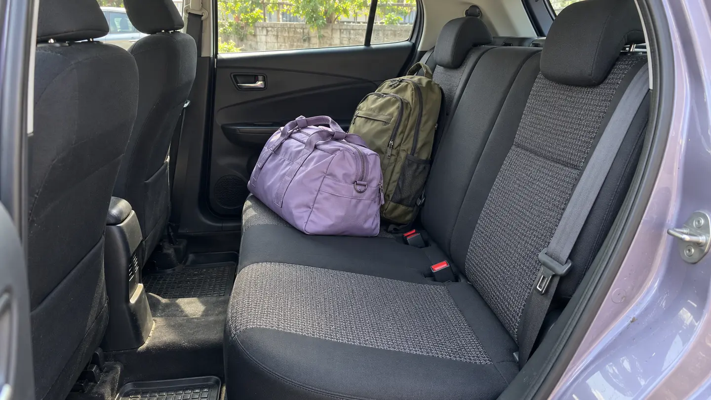A compact duffel and backpack beside an unused seating position in a parked hatchback